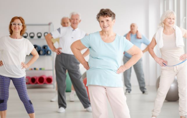 Happy seniors doing stretches and exercising in senior community gym