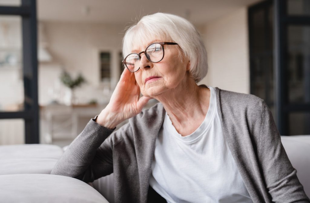 An older adult sitting thoughtfully, highlighting potential signs of social isolation or declining well-being.