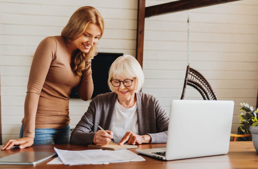 A woman assisting a senior with dementia with an administrative task or activity, offering support and guidance.