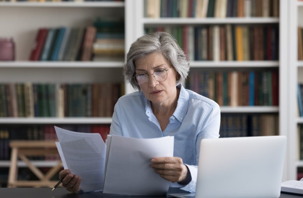 An older adult wearing glasses studies the services and amenities at different retirement communities while trying to choose a place to retire.